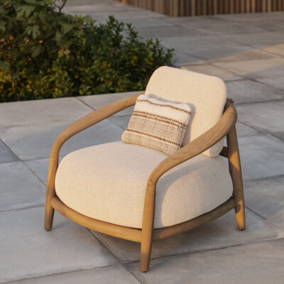 Outdoor lounge chair with curved wooden arms and beige cushion on a tiled patio, with a striped throw pillow.