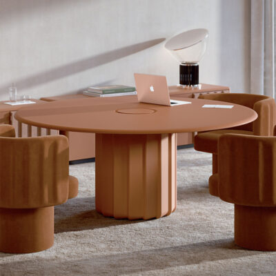 Round peach-colored conference table with a laptop and notebook, surrounded by plush matching chairs in a modern lounge.